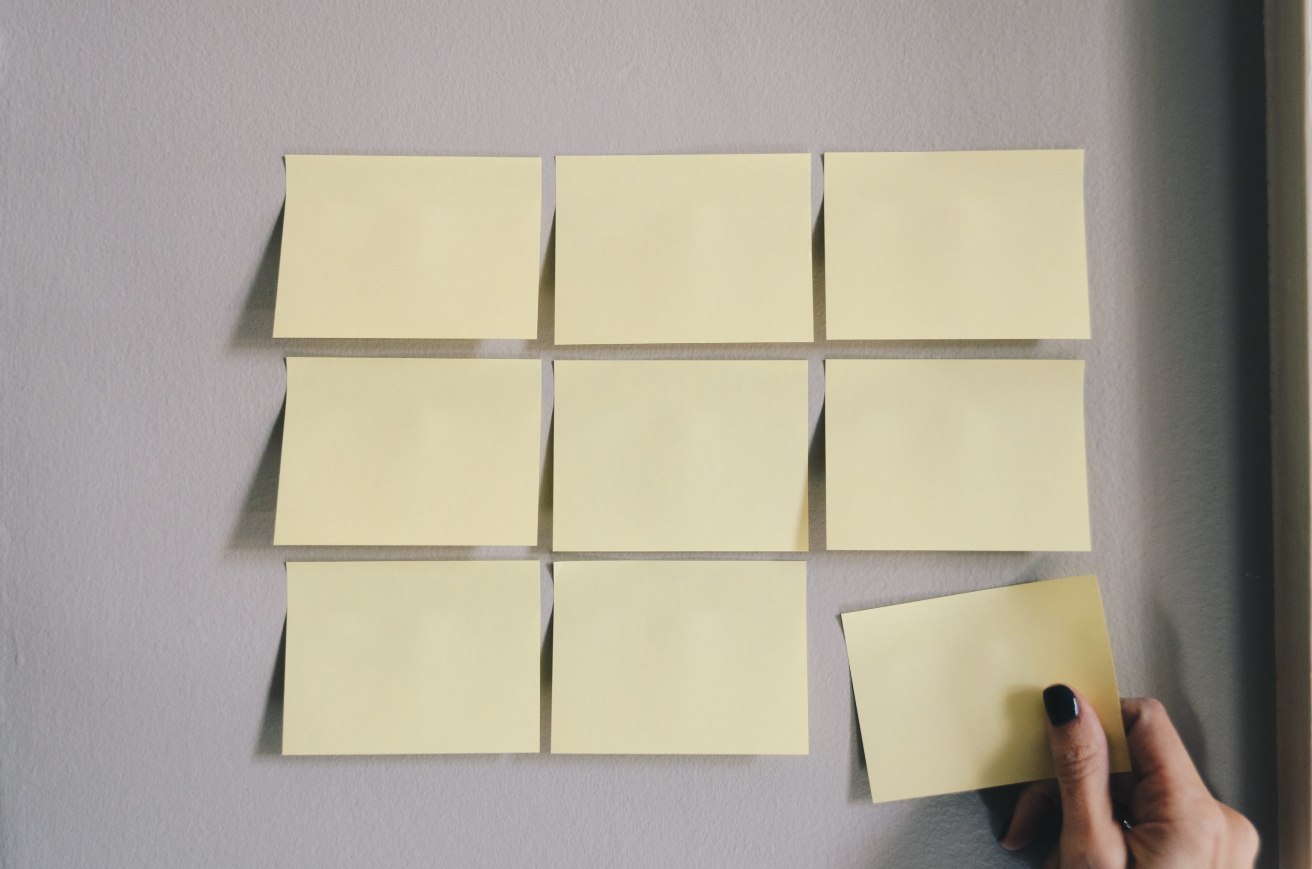 des post-its blancs déposés en puzzle avec une main féminine qui colle le dernier